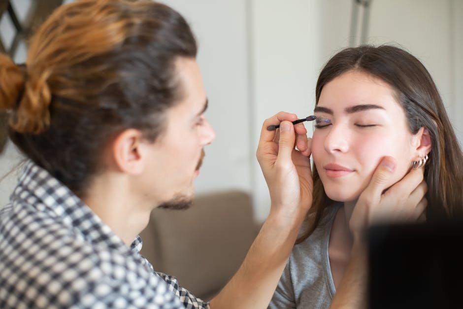 Close-up of a makeup artist applying eyeliner to a woman's eyes in a professional setting