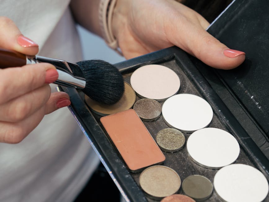 Female hands holding a makeup brush and palette for cosmetic application
